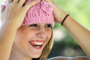 A girl in a pink hat smiling after a dental checkup in Lansdale.