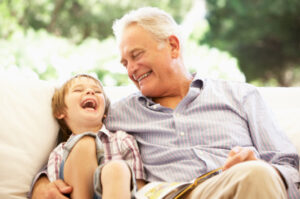 A granfather smiling with restored teeth next to his grandchild.