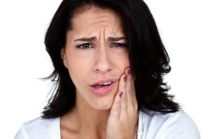 A young woman clutching her jaw from untreated TMJ in Lansdale.
